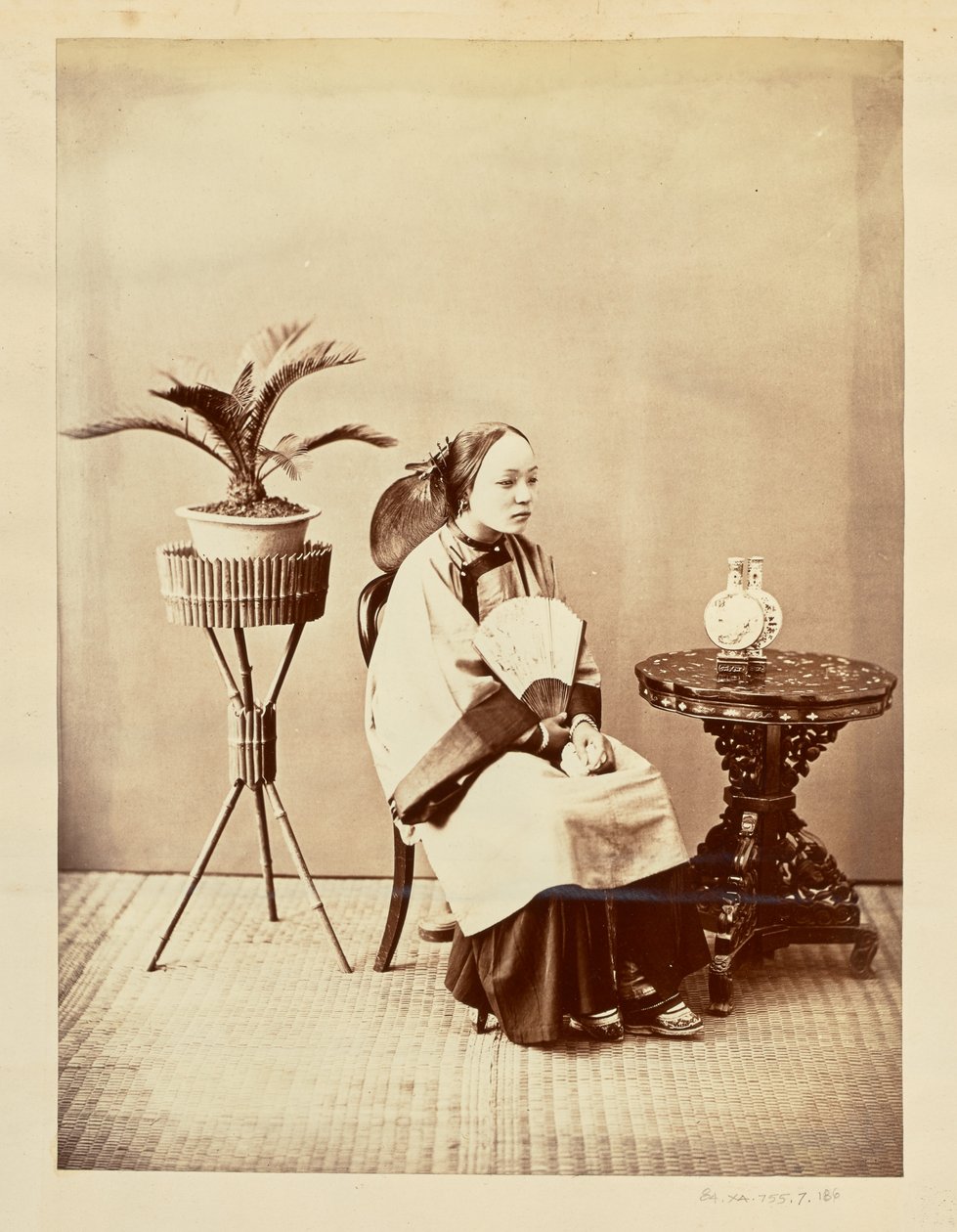 [Studioportret van een zittende jonge vrouw met een waaier]. door William Saunders