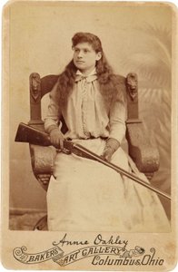 Annie Oakley: Hier zit de legendarische scherpschutter tamelijk bescheiden in een massieve Renaissance-stijl stoel, een geweer rustend op haar schoot. Haar delicate vrouwelijke trekken en vloeiende haar verbergen haar ruige buitenbeeld