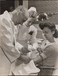 [Dokter en verpleegster steken een naald in de arm van een vrouw].