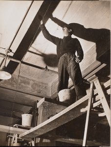 [Een man op een houten steiger schildert een plafond]. door Arnold Eagle