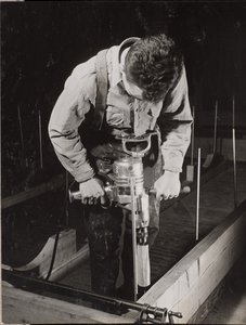 [Man gebruikt een handbediende machine om een stuk hout te bewerken]. door Arnold Eagle