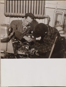 [Twee mannen werken aan een machine met een schroevendraaier en een moersleutel]. door Arnold Eagle