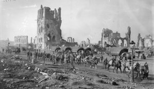 Een niet-geïdentificeerde Australische machinegeweersectie met bepakte paarden die de ruïnes van de Lakenhal passeren. Let op de geparkeerde motorvrachtwagens op de achtergrond, 19 oktober 1917 door Australian Photographer