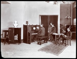 Vier mannen, een speelt op een H. Bruman Co. pianola, 1907 door Byron Company
