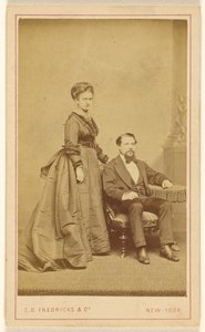 [Ongeïdentificeerd paar: vrouw staand, man met Vandyke baard zittend].