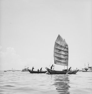 Een sampan onder zeil en een die wordt geroeid in de haven van Penang