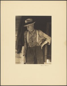 [Besnorde oude man met strohoed en bretels staat in de deuropening]. door Doris Ulmann
