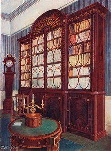 Ingelegd mahonie boekenkast. Mahonie voetstuk midden tafel. Mahonie hoge kast klok