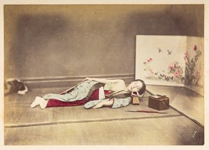 Japanse vrouw die slaapt, Studioportret van een jonge Japanse vrouw die slaapt, met een ontbloot borst en haar hoofd rustend op een houten kussen door English Photographer