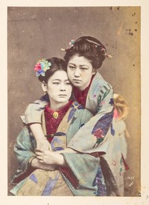 Japanse vrouwen in traditionele kleding, Driekwart lengte portret van twee jonge vrouwen, een zittend, de ander leunend over haar schouder met haar armen om haar heen