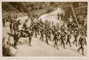 Angelsaksische broederschap in wapens: Amerikaanse troepen geleid door een Britse band marcheren langs een Britse generaal in Frankrijk door English School