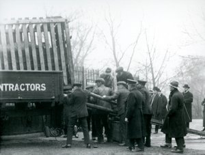 Een menigte toeschouwers staat erbij terwijl een neushoorn uit een vrachtwagen wordt gelost door verzorgers, London Zoo in 1924 door Frederick William Bond