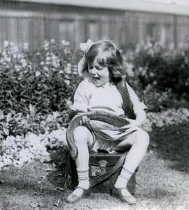Een jong meisje Betty houdt een oostelijke indigo-slang vast terwijl ze op een leren koffer zit, London Zoo, 1924 door Frederick William Bond