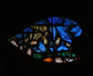 Het westelijke roosvenster met een scène uit het Boek Openbaring: opstanding van de getuigen en hun hemelvaart (in de blauwe wolken) terwijl de toeschouwers verbaasd zijn (11:11-13)