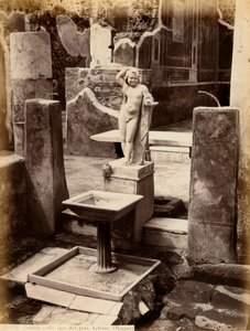 Een fontein bestaande uit een beeld van een naakte jongen. De fontein bevindt zich in het Huis van Balcone pensile, in Pompeii