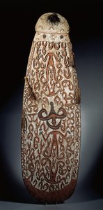 Ovale Asmat-schild, gesneden in reliëf met scrollende ornamenten met sterk gestileerde figuren, gevlochten kwastjes aan de rand