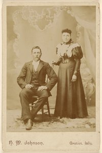 [Ongeïdentificeerd paar: man met snor zittend, vrouw staand].
