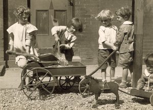 Jonge kinderen die grind in een kar laden door Jessie Tarbox Beals