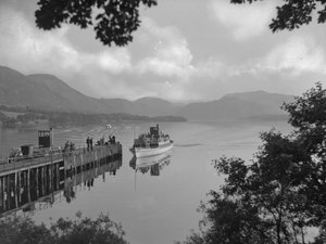 Een boot met mensen op een meer bij een steiger, bergen op achtergrond