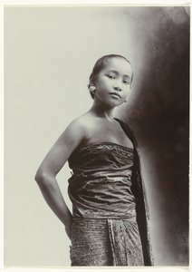 Studioportret van een jonge Javaanse vrouw in een sarong met batik motief door Kassian Cephas