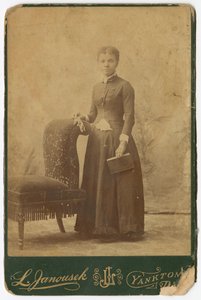 Foto van een vrouw die naast een stoel staat en een boek vasthoudt, laat 19e eeuw
