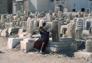 Jemenitische man reciteert de Koran op een begraafplaats met graven in Sayun, Hadramawt, Zuid-Jemen