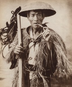Japanse koelie (landarbeider) met een hoed om hem te beschermen tegen zware regen in de rijstvelden (zw/w foto)