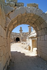 Uitzicht door de gewelfde ingang van het Xanthos-theater naar de orkestbak, met zuil en Harpy-tombe, Xanthos, Turkije