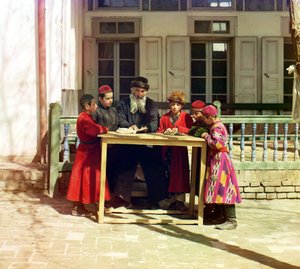 Een groep Joodse kinderen met een leraar aan een tafel voor een huis, Samarkand, Russisch Rijk, tussen 1905 en 1915