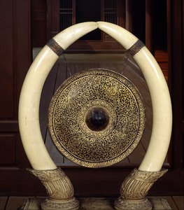 Een gong hangend aan olifantenslagtanden (metaal en ivoor)