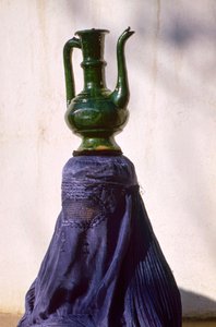 Vrouw in Kabul afgeschermd door zijden chadri, draagt kruik