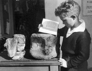 Palos Verdes, Californië: ca. 1927 Een jonge jongen bestudeert archeologie met behulp van een versteende prehistorische wervel gevonden in de nabijgelegen heuvels. door Unbekannt