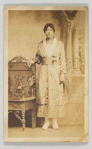 Fotografische ansichtkaart van een vrouw naast een houten stoel, 1904-1918 door Unbekannt