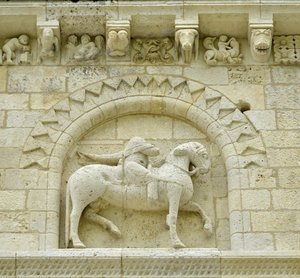 Romaans kunst: detail van de gevel die Hugues de Surgeres en Geoffroy de Vendome of keizer Constantijn de Grote afbeeldt, wiens paard de ketterij vertrapt en Christus triomfeert over het kwaad en de dood, Notre Dame de Surgeres