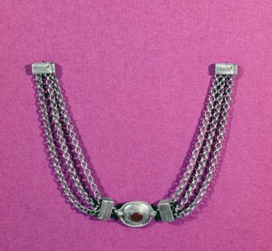 Zilveren ketting met een carneool, in een ovale setting omrand met een kabelrand, opgehangen tussen twee lengtes van drie kettingen vastgemaakt door een doosachtige sluiting, gevonden in Great Chesters, midden 1e tot
