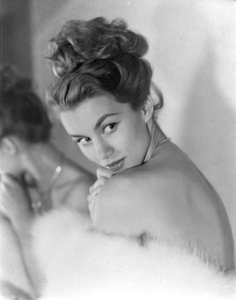 Een jonge vrouw kijkt verlegen over haar schouder, circa 1948: Knipogend