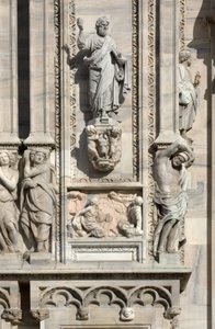 Architectuur: standbeeld van Sint Lucas (1811), en laag reliëf dat de verschijning van de engel aan de moeder van Samson voorstelt (1659). Detail van de gevel van de kathedraal (dom of duomo) van Milaan, Italië (detail)