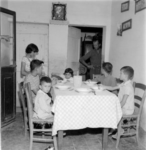 Grote familie verenigd aan tafel in de eetkamer van het landhuis. Jaren 1960 door Unbekannt