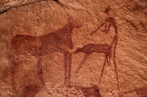 Rotstekeningen, Prehistorie: Rotsschildering van een koe, kalf en figuur (boogschutter) in een versierd onderkomen, in het Uweinat-massief, Egypte. Fotografie door Unbekannt