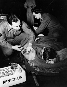 Tweede Wereldoorlog (1939-1945): Luxemburg februari 1945: In een evacuatieziekenhuis van het Amerikaanse leger dient een medicus (verpleegster) penicilline toe aan een gewonde soldaat om infectie te voorkomen terwijl een verpleegster hem voorbereidt op een