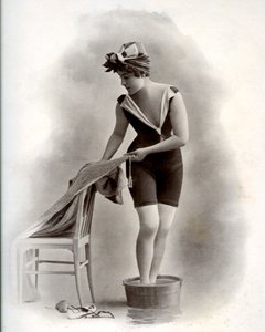 Jonge vrouw in badpak (uit de Belle Epoque) neemt een voetbad, rond 1900 (zwart-wit foto)