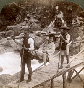 Japanse vrouw in een yamakago bergstoel die de stromende Daiya rivier bij Nikko, Japan, oversteekt door Underwood and Underwood