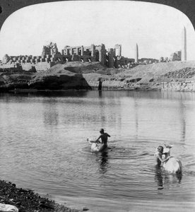 Uitzicht over het Heilige Meer naar de grote tempel in Karnak, Thebe, Egypte door Underwood and Underwood