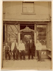 [Vier mannen en een jongen staan voor een openbaar badhuis]. door Unknown artist