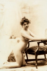 Naaktportret van een jonge vrouw knielend voor een kleine fauteuil door Unknown photographer