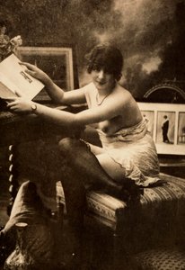 Portret van een jonge vrouw in intieme kleding, zittend aan een tafel met een boek