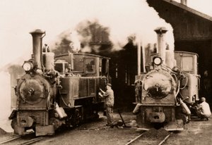 Twee stoomlocomotieven worden onderhouden door twee arbeiders door Unknown photographer