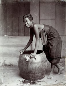 Jonge glimlachende Thaise vrouw, duwt een grote container