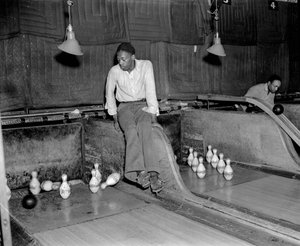 Afrikaans-Amerikaanse man bij bowlingbaan, handmatig de kegels opnieuw opzetten