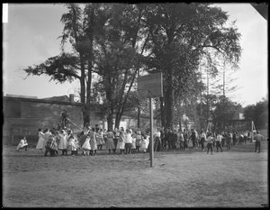 Jongens en meisjes spelen touwtrekken op een onbekende speelplaats, c.1910